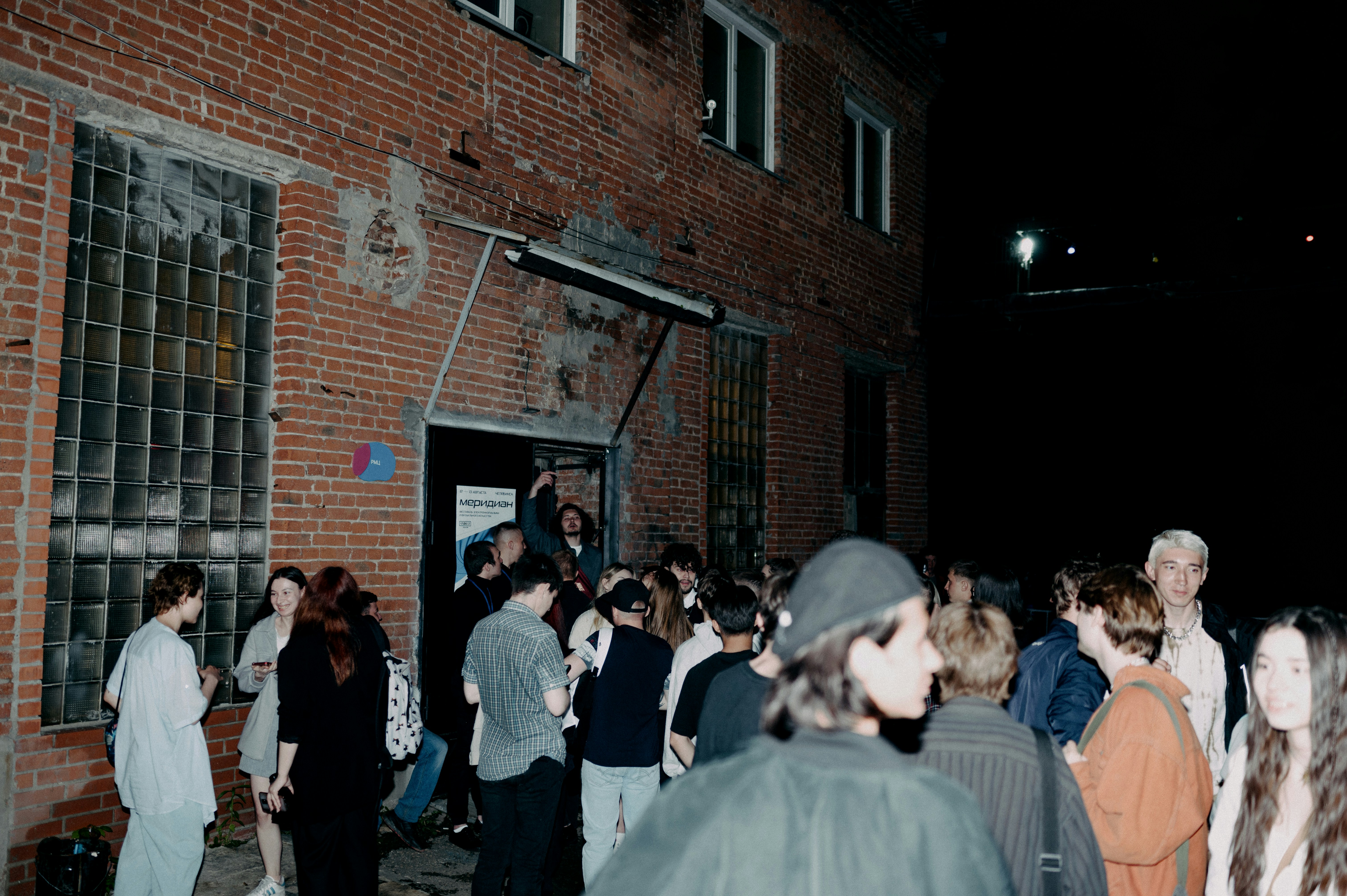 A crowd gathered outside a brick venue at night